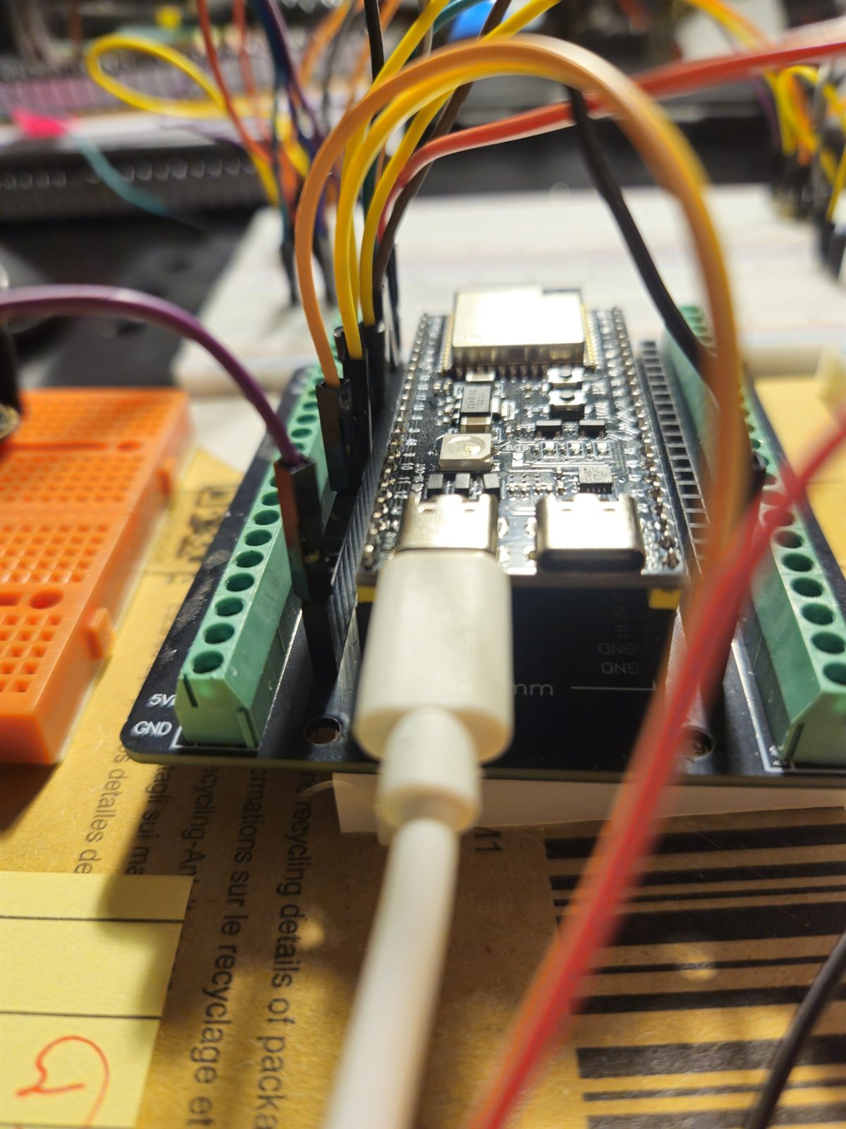 Close view of the ESP32-S3 board with USB-C connected and wires leaving the terminal blocks
