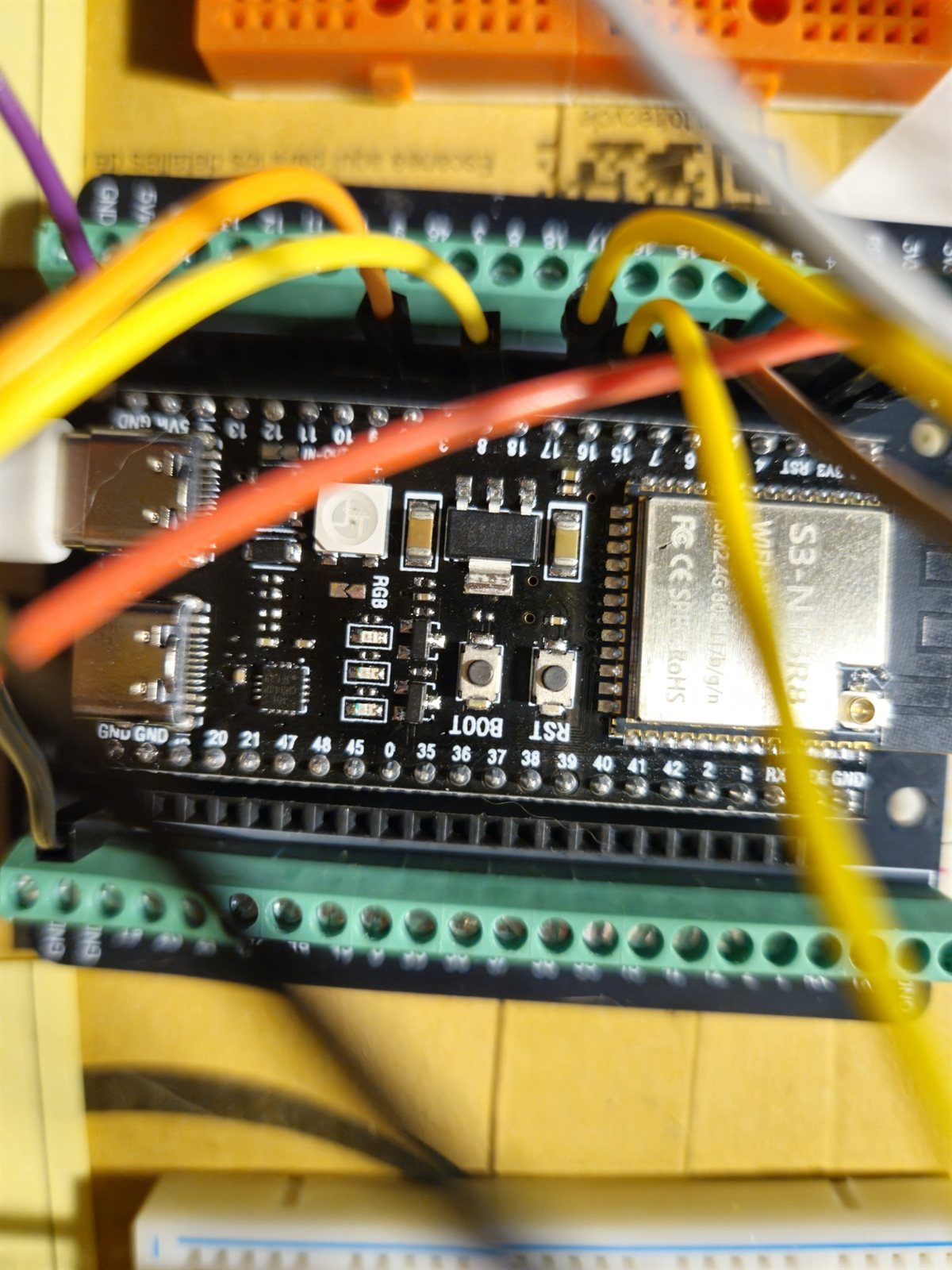 Macro photograph of the ESP32-S3-N16R8 module showing the BOOT and RST buttons and pin labels
