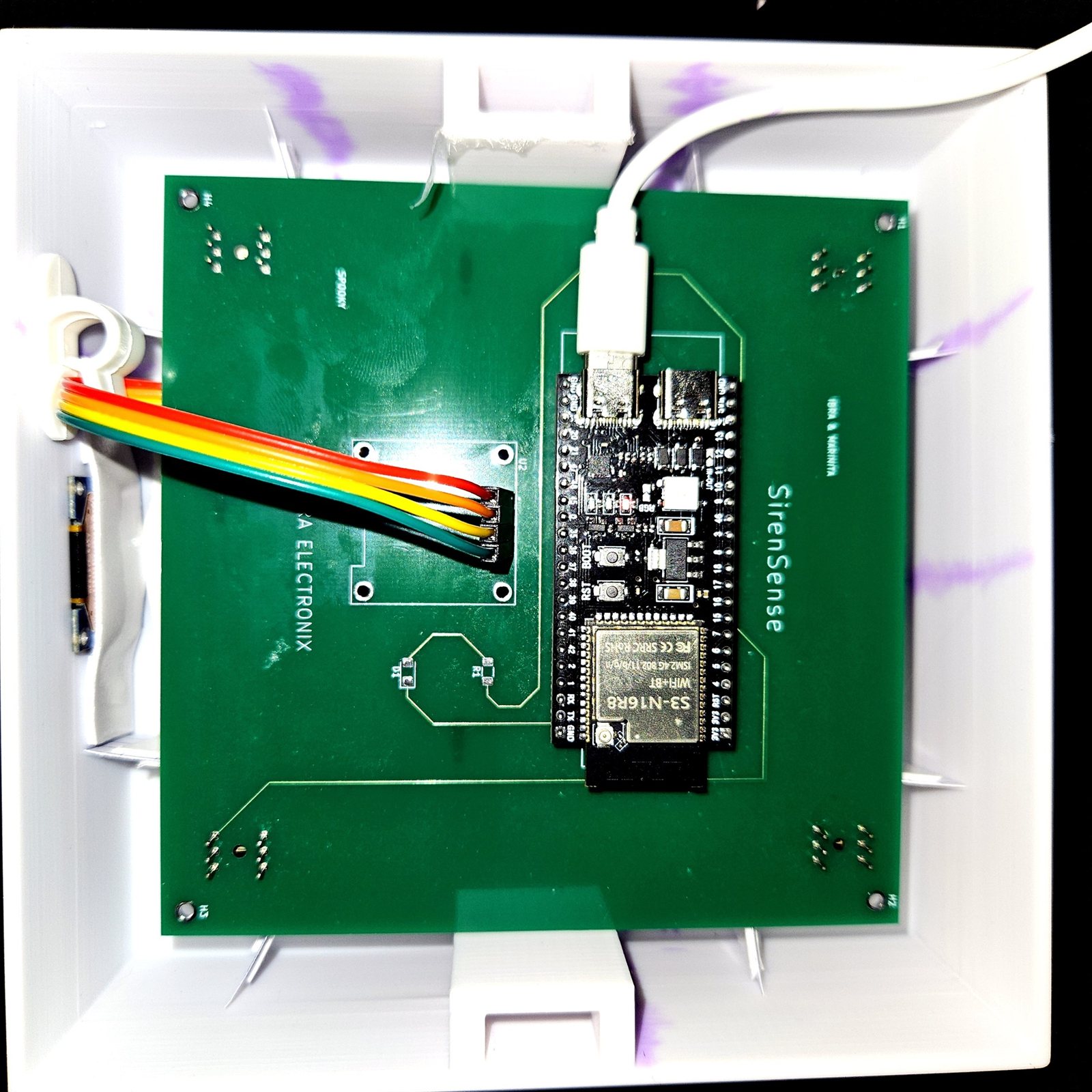 The green SirenSense REV 1 circuit board mounted inside the white printed enclosure
